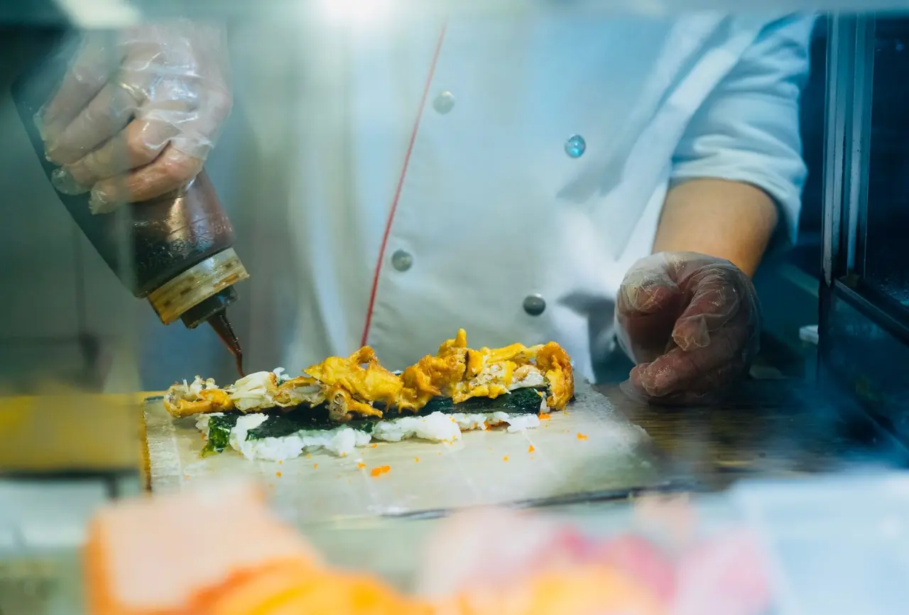 Chef applying finishing brush of glaze to sushi
