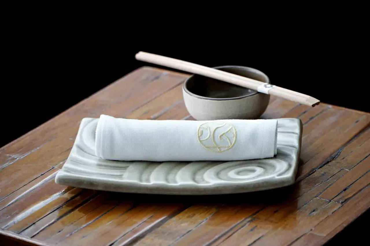 Clean ceramic table setting with chopsticks and rolled linen