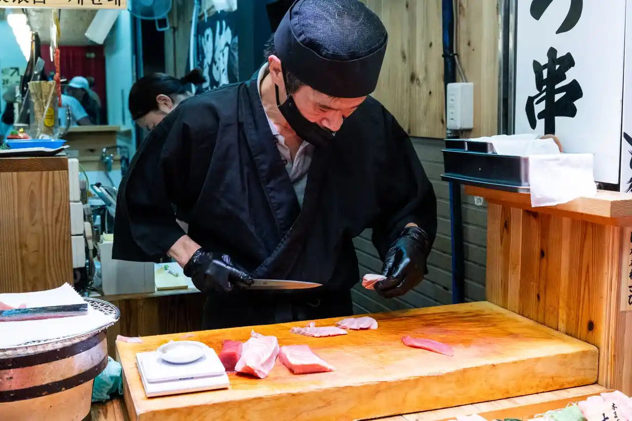 Sushi chef slicing fresh fish carefully with a Japanese knife