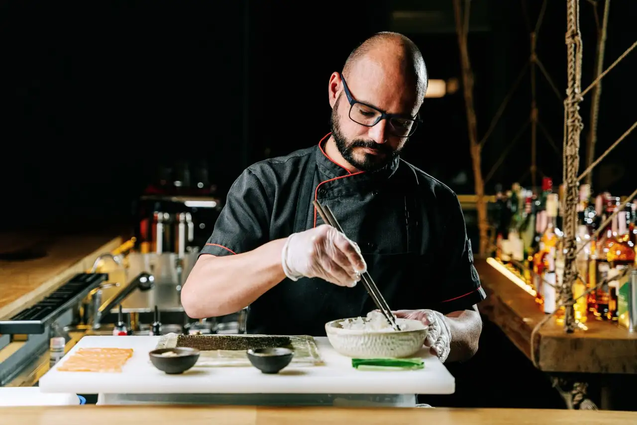 Skilled sushi chef carefully crafting sushi with precision and art in a contemporary kitchen setting