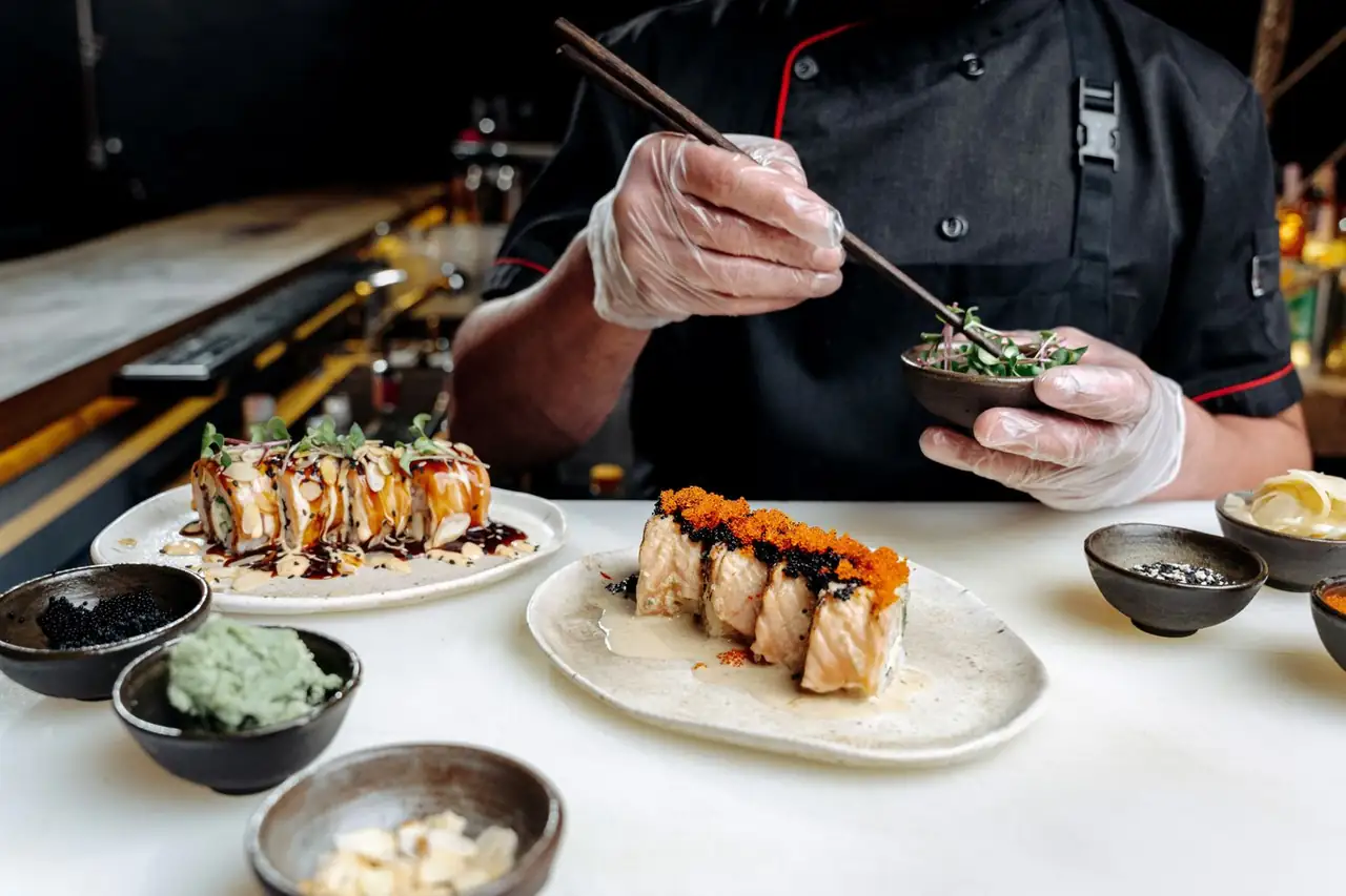 Sushi chef precisely arranging freshly sliced ingredients in kitchen